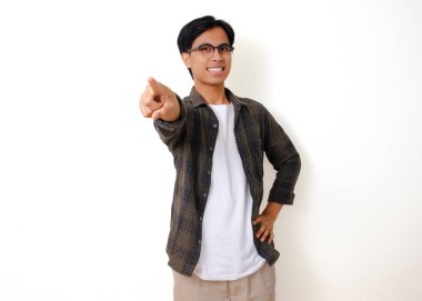Mutlu, heyecanlı genç Asyalı adam gülümseyip kamerayı işaret ediyor, izole beyaz arka planda duruyor.