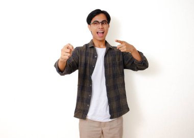 Heyecanlı genç Asyalı adam ayakta duruyor ve beyaz bir arka planda izole edilmiş mutlu bir ifadeyle boş bir kese ilacı ürünü gösteriyor.