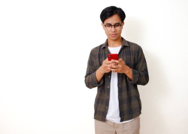 Beyaz bir arka planda izole edilmiş cep telefonu kullanan kendine güvenen genç Asyalı adam.
