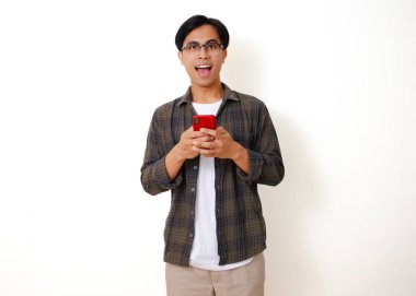Beyaz bir arka planda izole edilmiş cep telefonu kullanan kendine güvenen genç Asyalı adam.