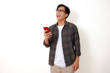 Beyaz bir arka planda izole edilmiş cep telefonu kullanarak ayakta durup gülen mutlu Asyalı genç adam.
