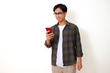Beyaz bir arka planda izole edilmiş cep telefonu kullanan kendine güvenen genç Asyalı adam.