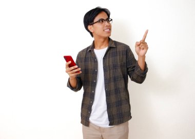 Yan tarafı gösterirken elinde cep telefonu tutan heyecanlı Asyalı genç adam, beyaz bir arka planda izole edilmiş.