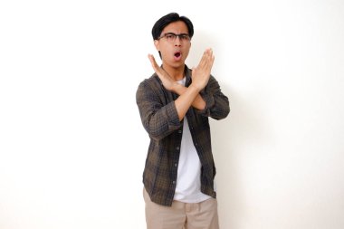 Hayır, ciddi Asyalı genç adam beyaz bir arka planda izole bir şekilde el hareketi yapıyor.