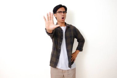 Hayır, ciddi Asyalı genç adam beyaz bir arka planda izole bir şekilde el hareketi yapıyor.