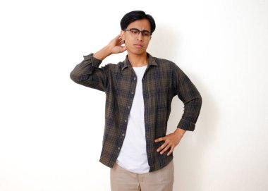 Stresli, genç Asyalı bir adam beyaz arka planda izole edilmiş, kafası karışmış bir ifadeyle başını kaşıyor.