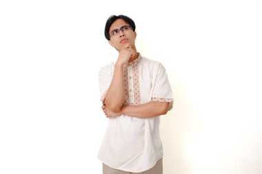 Endonezyalı Müslüman bir adamın portresi, beyaz arka planda izole edilmiş, düşünce, planlama ve karar verme şeklini sembolize eden bir düşünce jesti gösteriyor.