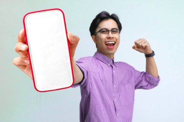 Akıllı telefon tutan ve mutlu bir şekilde gülümseyen genç bir adam..