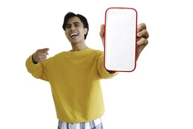 Heyecanlı Asyalı genç adam gülümserken boş bir akıllı telefon ekranını işaret ediyor, beyaz arka planda izole edilmiş, model, dijital promosyon ve çevrimiçi reklam için mükemmel..