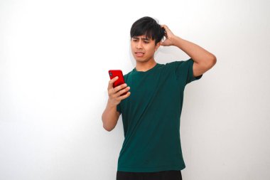 Cep telefonuna bakarken kafası karışmış ve stresli görünen Asyalı genç bir adamın portresi.