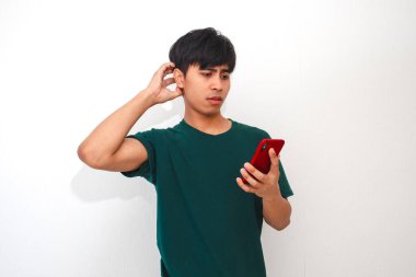 Cep telefonuna bakarken kafası karışmış ve stresli görünen Asyalı genç bir adamın portresi.