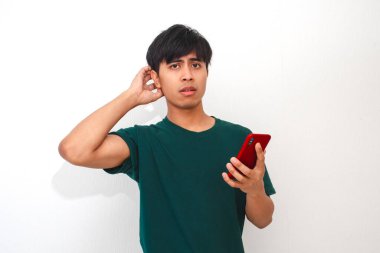 Cep telefonuna bakarken kafası karışmış ve stresli görünen Asyalı genç bir adamın portresi.