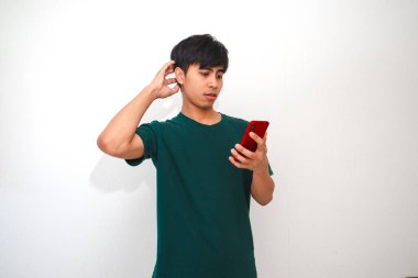 Cep telefonuna bakarken kafası karışmış ve stresli görünen Asyalı genç bir adamın portresi.