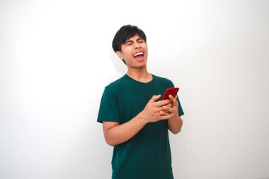 Beyaz arka planda izole edilmiş akıllı bir telefonla gülen Asyalı genç bir adamın portresi. Reklam, teknoloji, iletişim ya da yaşam tarzı kavramları için mükemmel.