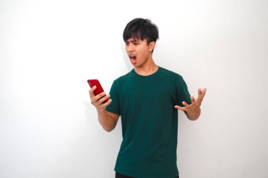 Kızgın Asyalı genç adam, sinirli bir ifadeyle akıllı telefona bakıyor.