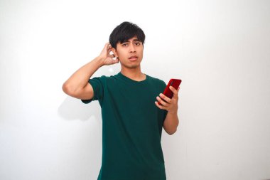 Cep telefonuna bakarken kafası karışmış ve stresli görünen Asyalı genç bir adamın portresi.