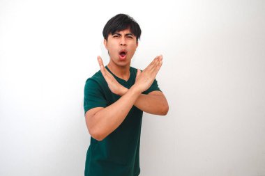 Durup kameraya bakan ciddi bir Asyalı genç adamın portresi. Tarafsız bir arkaplanda izole edilmiş bir el hareketi yapıyor. Reklamcılık için ideal.