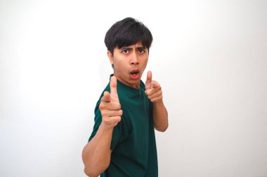 Genç bir Asyalı adam komik ve çekici bir ifadeyle kamerayı şakaya vurur. Düz beyaz bir arka planda koyu yeşil bir tişört giyiyor.