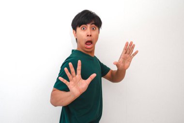 Şaşırmış ve hayal kırıklığına uğramış Asyalı genç bir adam geniş gözlü ve ağzı açık komik bir yüz yapıyor, beyaz arka planda izole edilmiş, tepki, duygu veya reklam kavramları için mükemmel.