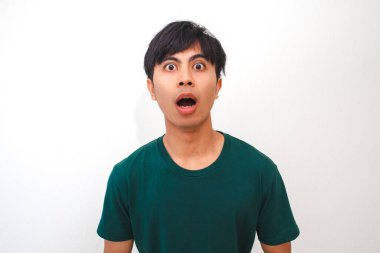 Şaşırmış ve hayal kırıklığına uğramış Asyalı genç bir adam geniş gözlü ve ağzı açık komik bir yüz yapıyor, beyaz arka planda izole edilmiş, tepki, duygu veya reklam kavramları için mükemmel.