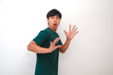 Yüzünde komik bir ifadeyle şok olmuş ve şaşırmış genç bir Asyalı adam beyaz arka planda izole edilmiş, reklam, tepki veya duygu konsepti için mükemmel.