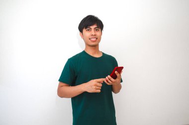 Akıllı telefonu tutan gülümseyen Asyalı genç adam, ekranda dikilirken, izole beyaz arka planda duruyor. Reklam, teknoloji veya yaşam tarzı içeriği için mükemmel