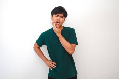 Acı dolu bir ifadeyle çenesine dokunan genç bir Asyalı, muhtemelen diş ağrısı yüzünden, beyaz arka planda izole edilmiş. Diş bakımı, sağlık ve tıbbi reklamlar için mükemmel.