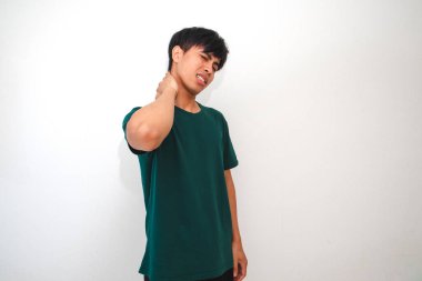 Genç Asyalı bir adam acı dolu bir ifadeyle boynuna dokunuyor, izole beyaz bir arka plana karşı duruyor. Sağlık, stres ve tıbbi reklamlar için uygundur
