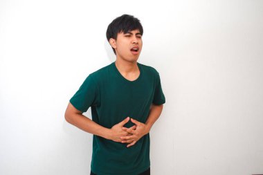 Genç Asyalı bir adam midesi ağrıyan bir mide ağrısı yaşıyor. Beyaz bir arka plan karşısında duruyor. Sağlık ve tıbbi reklam kavramları için mükemmel.
