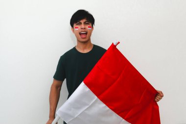 Heyecanlı Endonezyalı adam bayrak tutuyor ve sevinçle bağırıyor. Beyazların izole edilmiş arka planında başarıyı kutluyor. Bağımsızlık günü, zafer ve reklam temaları için mükemmel..