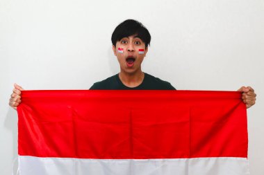 Heyecanlı Endonezyalı adam bayrak tutuyor ve sevinçle bağırıyor. Beyazların izole edilmiş arka planında başarıyı kutluyor. Bağımsızlık günü, zafer ve reklam temaları için mükemmel..