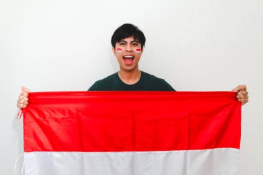 Heyecanlı Endonezyalı adam bayrak tutuyor ve sevinçle bağırıyor. Beyazların izole edilmiş arka planında başarıyı kutluyor. Bağımsızlık günü, zafer ve reklam temaları için mükemmel..