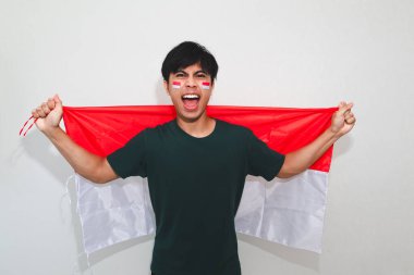 Heyecanlı Endonezyalı adam bayrak tutuyor ve sevinçle bağırıyor. Beyazların izole edilmiş arka planında başarıyı kutluyor. Bağımsızlık günü, zafer ve reklam temaları için mükemmel..