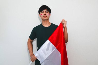 Bağımsızlık Günü kutlamaları için ulusal bayrak tutan kendine güvenen Endonezyalı adam, beyaz izole arka planda gururla duruyor, vatanseverlik, şenlik ve reklam kullanımı için mükemmel..