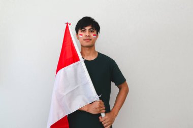 Bağımsızlık Günü kutlamaları için ulusal bayrak tutan kendine güvenen Endonezyalı adam, beyaz izole arka planda gururla duruyor, vatanseverlik, şenlik ve reklam kullanımı için mükemmel..