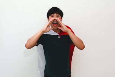 Heyecanlı Endonezyalı bir adam elinde bayrak tutarak mutlu bir ifadeyle anons yapıyor, beyaz bir arkaplanda izole edilmiş, kutlama ya da reklam için mükemmel..