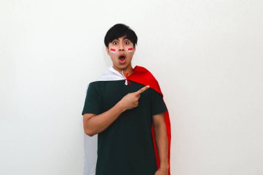 Heyecanlı Endonezyalı bir adam elinde bir bayrak, boş fotokopi alanını işaret ediyor, beyaz arka planda izole edilmiş, reklam ve kutlama kavramları için mükemmel..