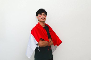 Omzunda bayrak olan kendine güvenen Endonezyalı adam beyazların izole geçmişinde gururla duruyor bağımsızlık kutlamaları, vatansever temalar ve reklamlar için mükemmel..