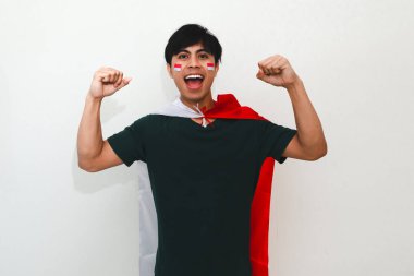 Heyecanlı genç Asyalı adam Endonezya 'nın Bağımsızlık Günü' nü 17 Ağustos 'ta kutluyor. Elinde Endonezya bayrağını tutarak ve beyaz arka planda izole edilmiş yumruğunu sıkarak.