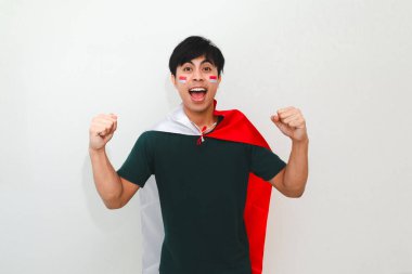 Heyecanlı genç Asyalı adam Endonezya 'nın Bağımsızlık Günü' nü 17 Ağustos 'ta kutluyor. Elinde Endonezya bayrağını tutarak ve beyaz arka planda izole edilmiş yumruğunu sıkarak.