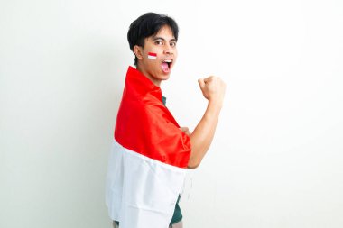 Endonezya bayrağını tutan ve gururla güçlü bir jest yapan kendinden emin genç Endonezyalı adam.