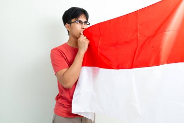 17 Ağustos 'ta Bağımsızlık Günü' nü kutlayan Endonezyalı genç bir adam gururla Endonezya bayrağını tutar ve öper.