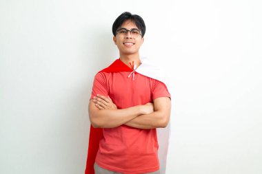 Endonezyalı genç bir adam, Endonezya bayrağını tutarak güvenle gülümsüyor, kollarını kavuşturup, 17 Ağustos 'taki Bağımsızlık Gününü kutluyor.