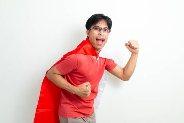 Endonezya bayrağıyla koşan heyecanlı Endonezyalı genç adam, 17 Ağustos 'ta Bağımsızlık Günü' nü kutluyor. İzole edilmiş arka planda enerjik vatanseverlik ifadesi, reklam kullanımı için mükemmel