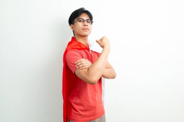 Bağımsızlık Günü 'nü kutlayan heyecanlı Endonezyalı genç adam, izole edilmiş arka planda gururlu bir ifadeyle elinde ulusal bayrak tutarken güçlü bir kol hareketi gösteriyor.