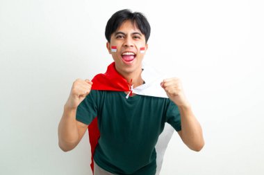 Heyecanlı Endonezyalı genç bir adam elinde ulusal bayrak ve sıkılmış bir yumrukla bağırıyor, Bağımsızlık Günü 'nü ruhuyla kutluyor, beyaz arka planda izole edilmiş bir şekilde.