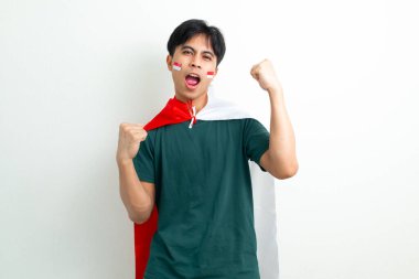 Heyecanlı Endonezyalı genç bir adam elinde ulusal bayrak ve sıkılmış bir yumrukla bağırıyor, Bağımsızlık Günü 'nü ruhuyla kutluyor, beyaz arka planda izole edilmiş bir şekilde.