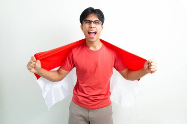 Heyecanlı Endonezyalı genç bir adam elinde ulusal bayrak ve sıkılmış bir yumrukla bağırıyor, Bağımsızlık Günü 'nü ruhuyla kutluyor, beyaz arka planda izole edilmiş bir şekilde.