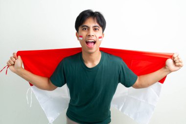 Bağımsızlık Günü 'nü kutlarken Endonezya bayrağını tutan heyecanlı genç adam, parlak bir arka planda izole edilmiş, reklamlar ve ulusal temalar için mükemmel.