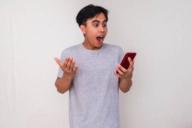 Genç adam işaret ederken heyecanla telefonunu tutuyor..